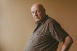 Ein glatzköpfiger, mittelalter Mann mit einem dicken Bauch.