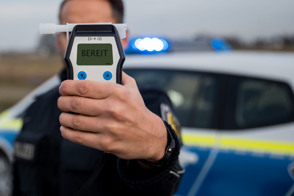 Ein Polizist hält ein Alkoholtest-Gerät in die Kamera.