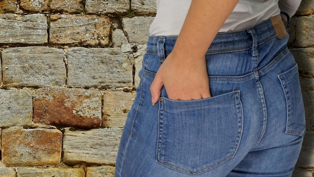 Eine Frau mit Jeans steckt ihre Hand in ihre Hosentasche.