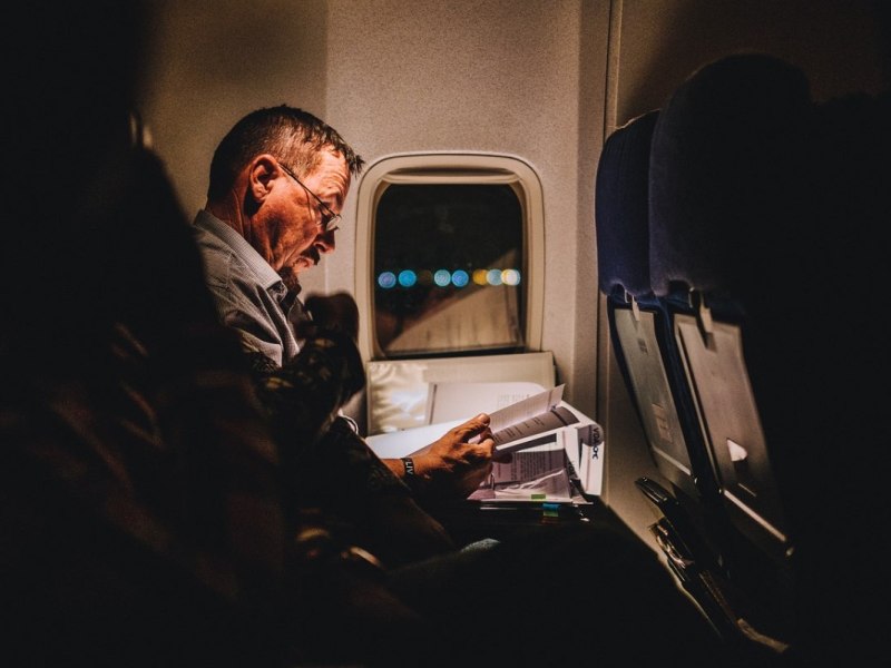 Ein Geschäftsmann liest im Flugzeug eine Zeitung.