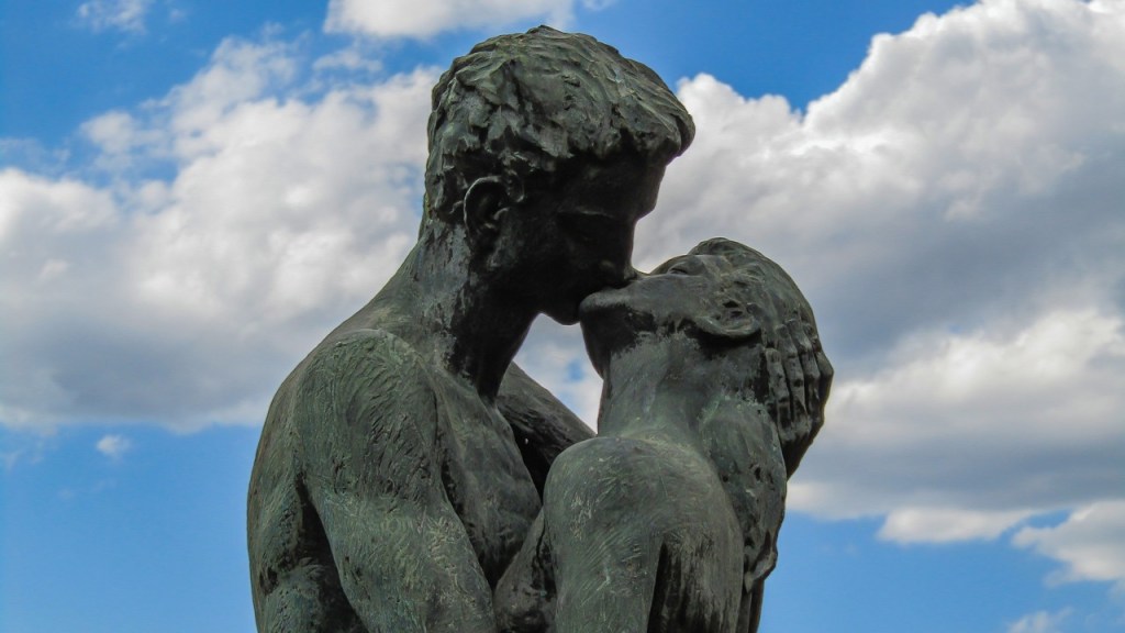 Eine Statue, die ein küssendes Paar zeigt, vor blauem Himmel.