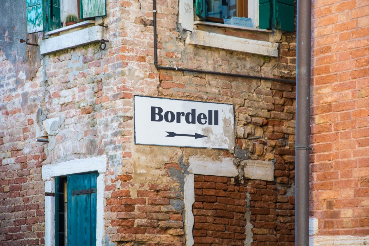 Ein Schild mit der Aufschrift 'Bordell' in einer alten Gasse.