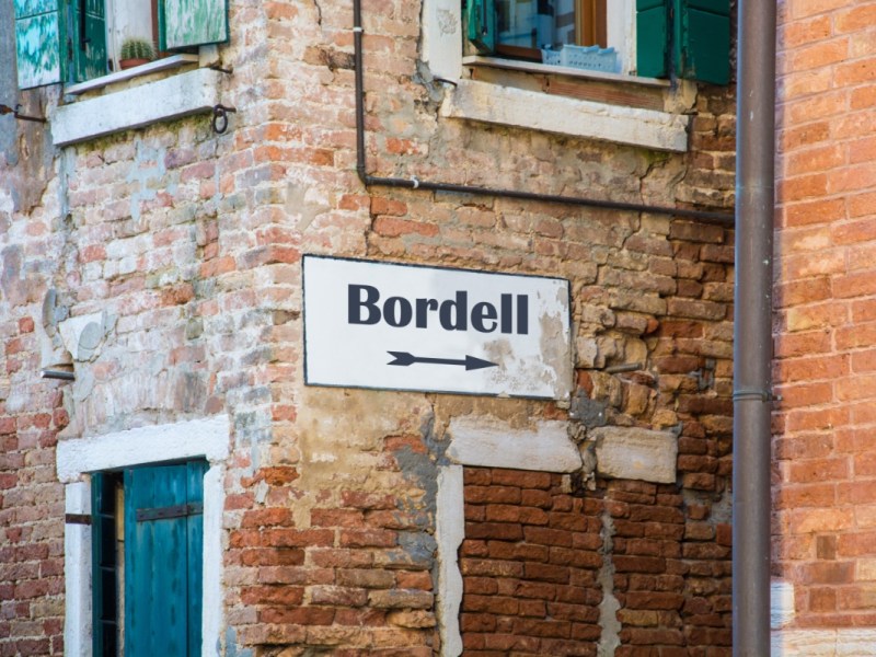 Ein Schild mit der Aufschrift 'Bordell' in einer alten Gasse.