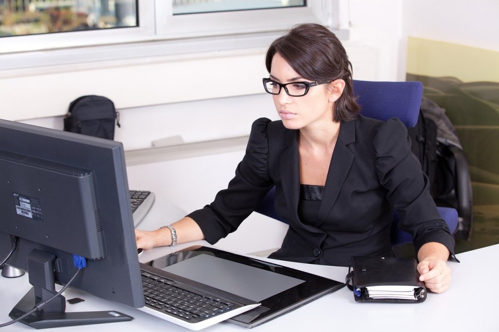 Eine Sekretärin im Büro sitzt vor einem Computer.