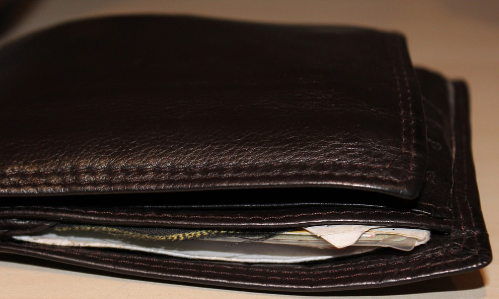 Ein gefülltes, schwarzes Portemonnaie liegt auf dem Tisch