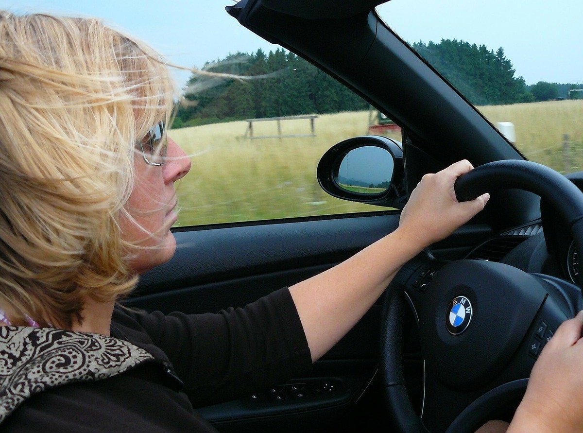 Eine Frau mit Sonnenbrille fährt in einem offenen Cabrio