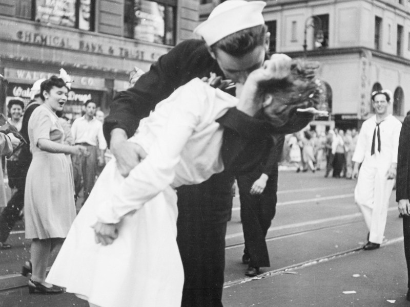 Ein historisches Foto in schwarzweiß von einer Frau, die auf dem Times Square, New York, von einem Soldaten geküsst wird.