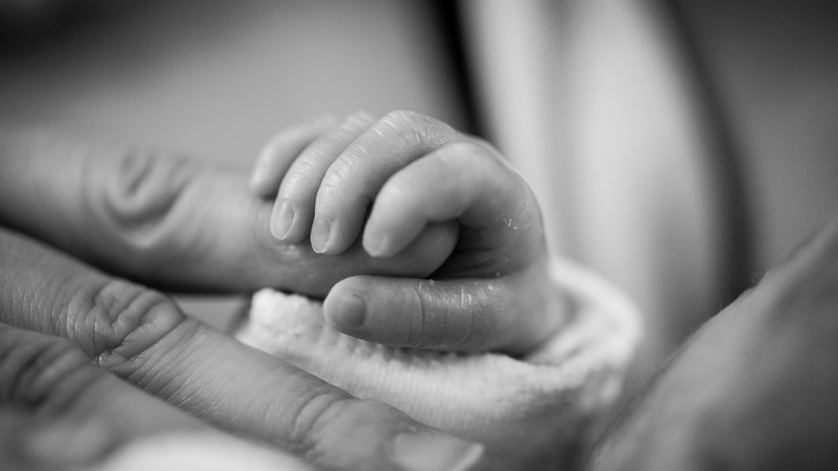 Ein Schwarzweiß-Foto von einem Baby, das den Finger seines Vaters festhält.