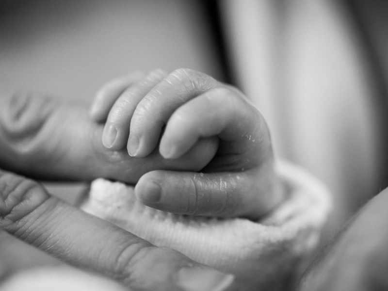 Ein Schwarzweiß-Foto von einem Baby, das den Finger seines Vaters festhält.