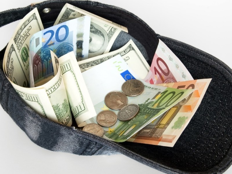 Euroscheine und Münzen in einer Schirmmütze.