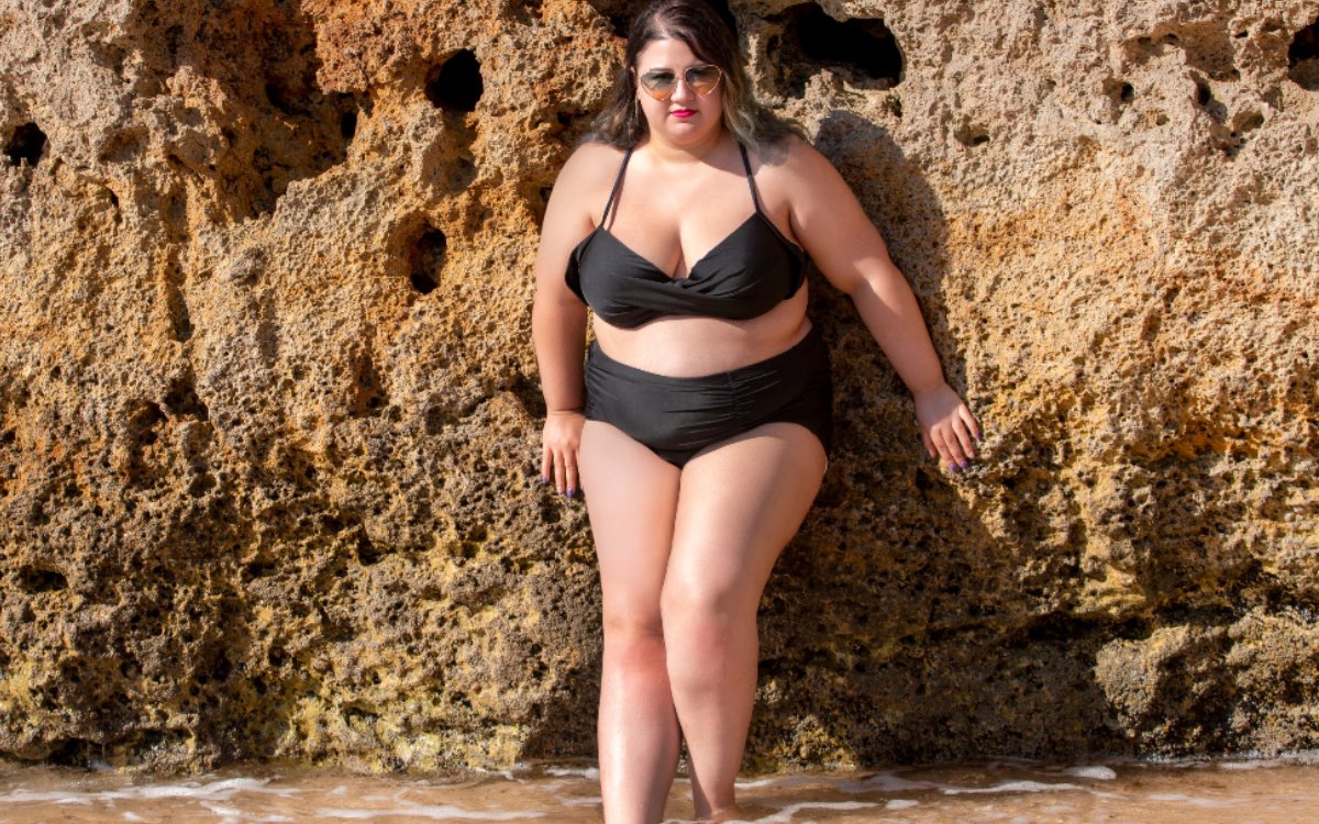 Eine vollschlanke Frau im Bikini an einem Strand.