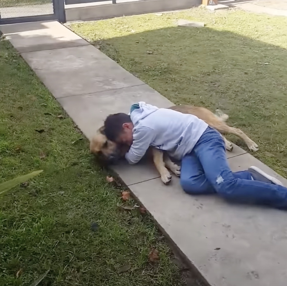 Ein Junge umarmt seinen Hund auf einem Gehweg.
