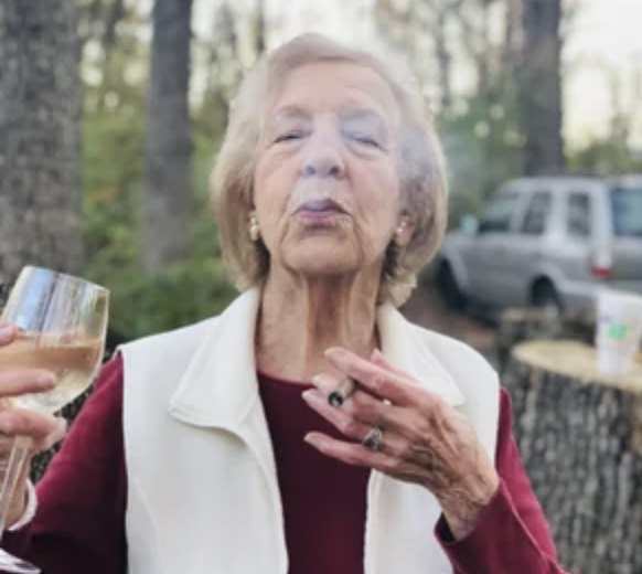 Alte Frau raucht und hält Weinglas