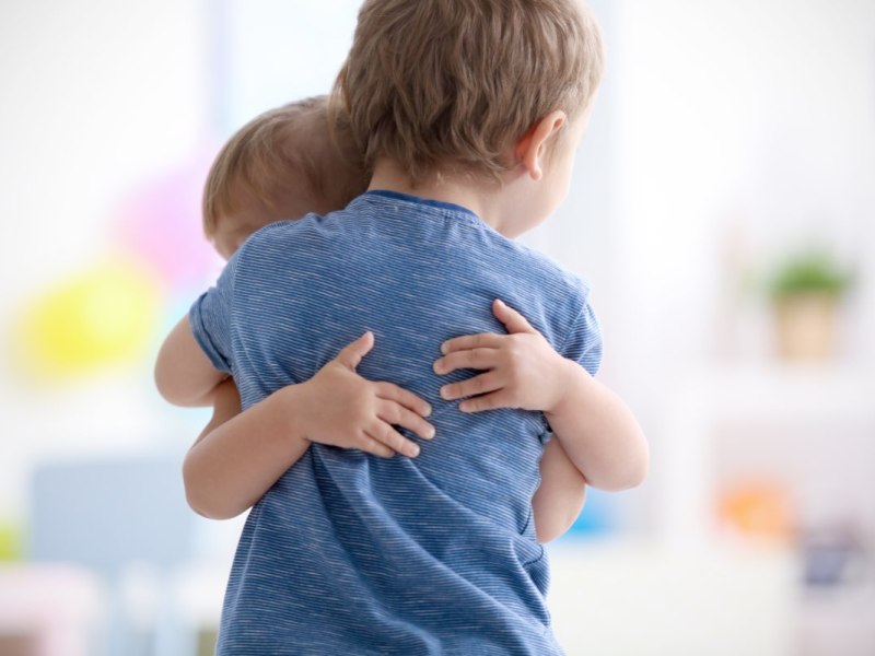 Zwei Kinder, ein Junge und ein Mädchen, umarmen sich.
