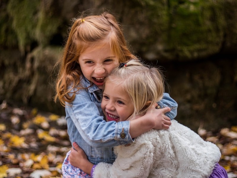 Zwei kleine Mädchen umarmen sich lachend.