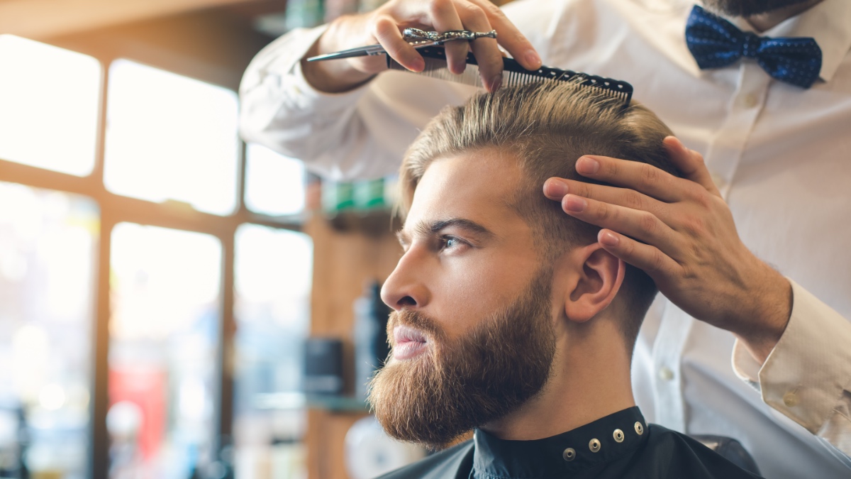 Ein junger Mann bekommt bei einem Friseur die Haare geschnitten.