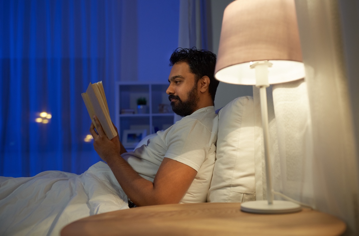 Ein Mann liegt in seinem Bett und liest ein Buch.