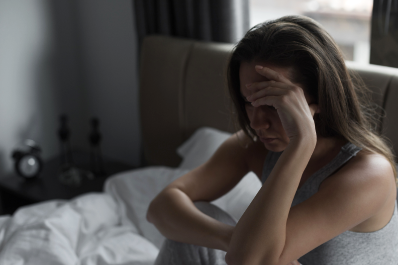 Eine Frau sitzt im Schlafanzug weinend im Bett