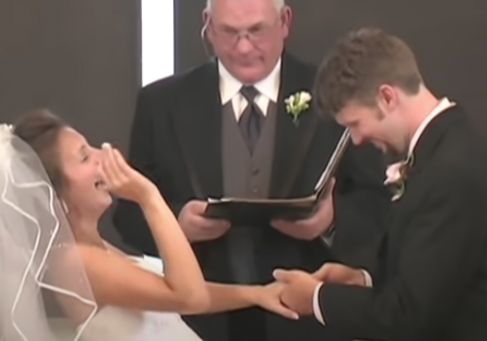 Eine Braut lacht beim Ehegelübde, während der Bräutigam den Ring ansteckt