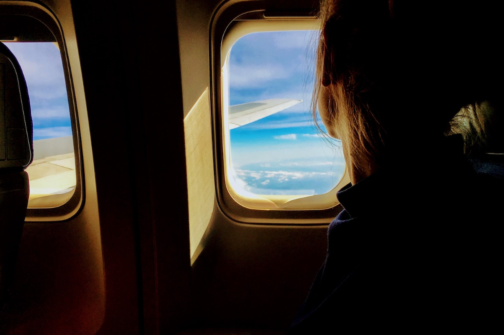 Eine Frau schaut im Flugzeug aus dem Fenster