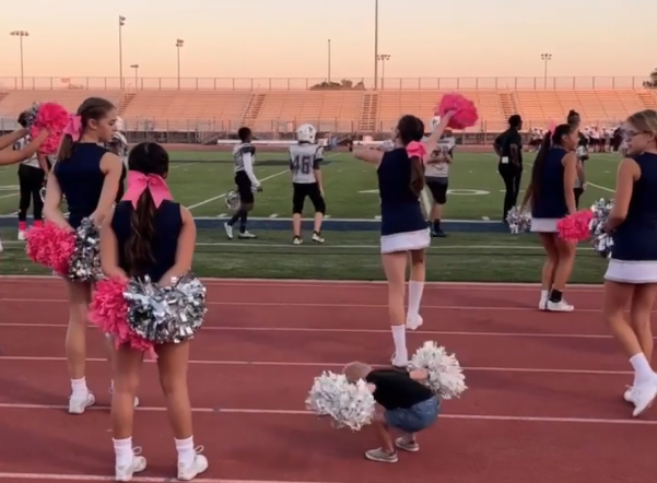 Ein kleiner Junge tanzt mit Cheerleadern