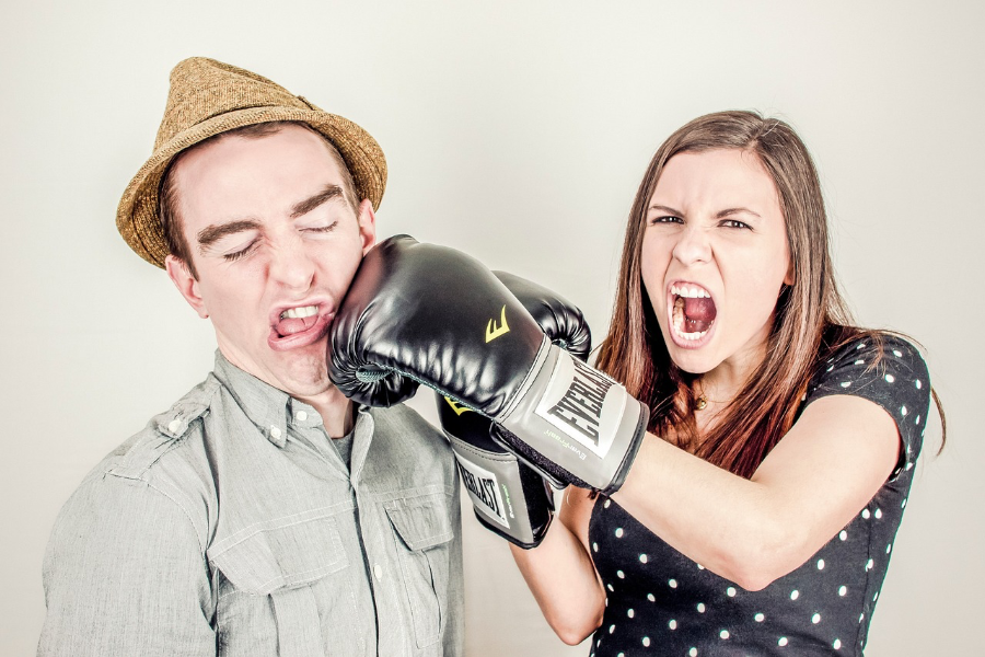Eine wütende Frau schlägt ihren Mann mit Boxhandschuhen.