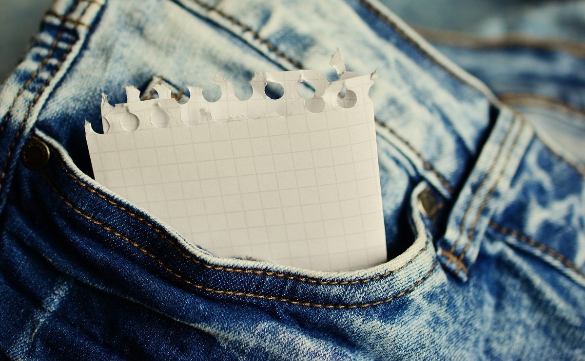 Ein zusammengefalteter Zettel in der Hosentasche einer Jeans.