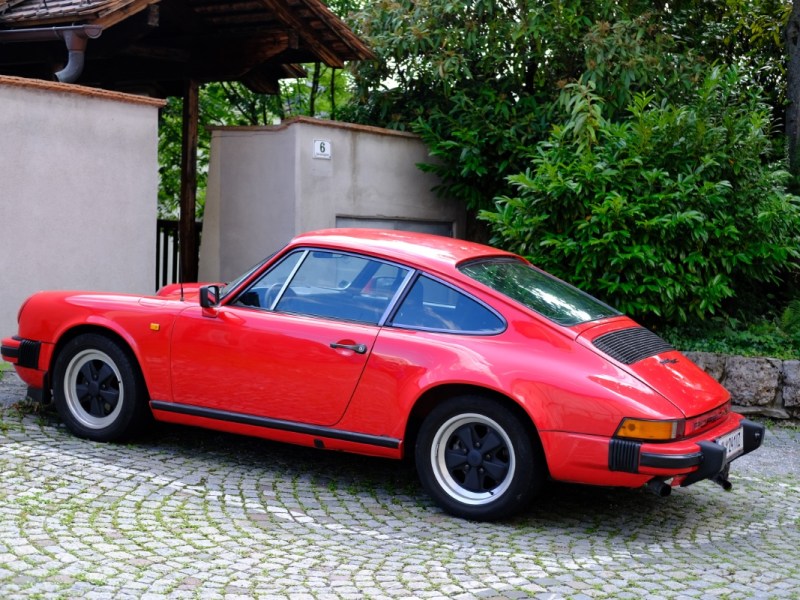 Ein roter Porsche parkt in einer Ausfahrt vor einem Haus.