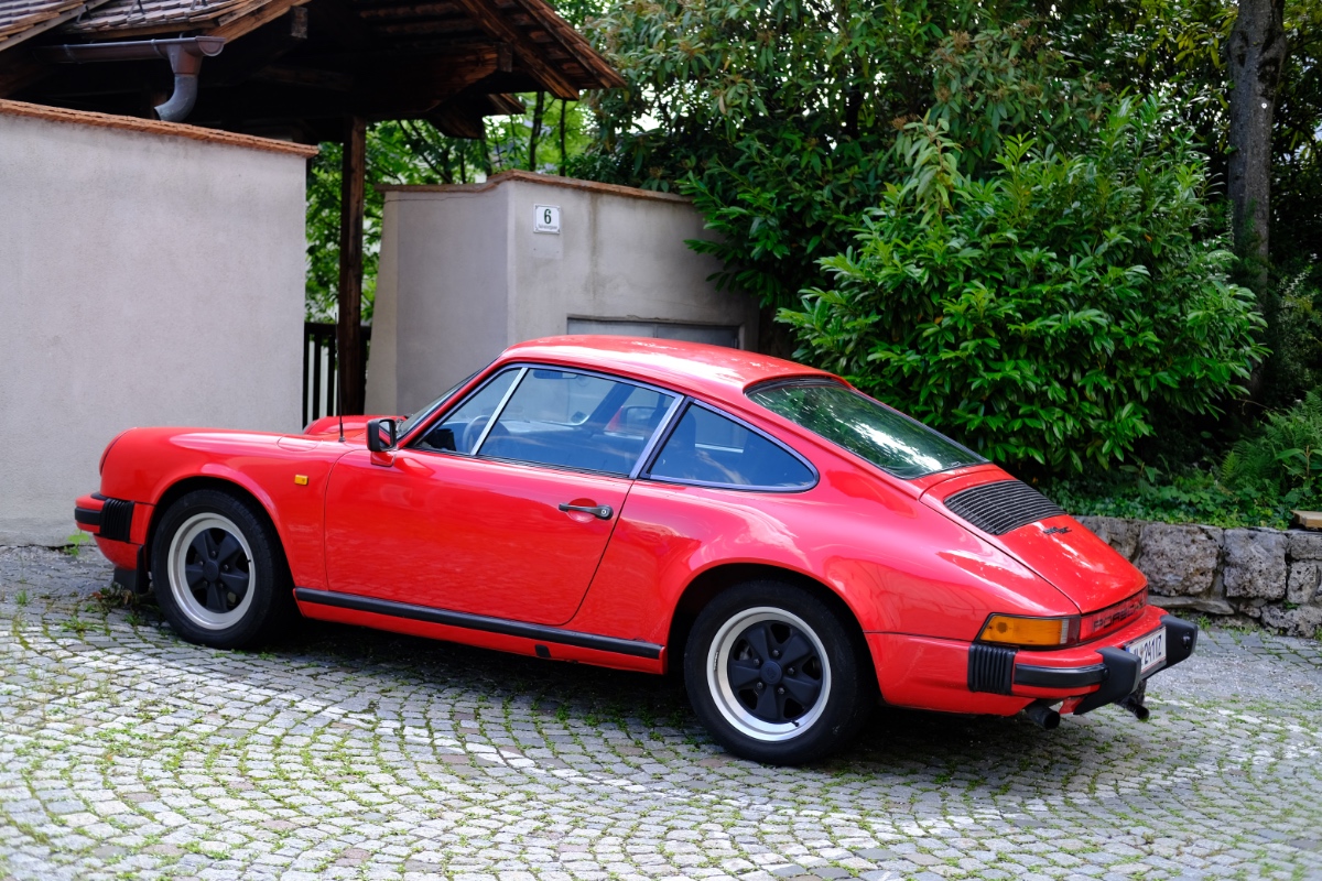 Ein roter Porsche parkt in einer Ausfahrt vor einem Haus.