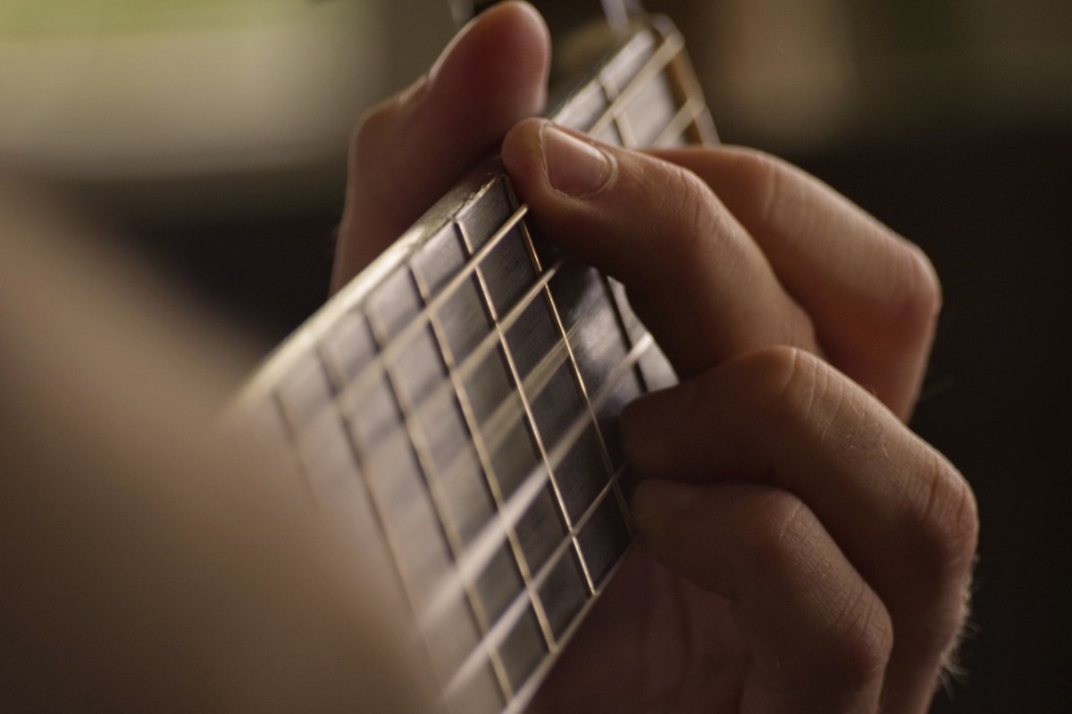Ein Foto von einer Hand, die einen Akkord auf einer Gitarre greift.