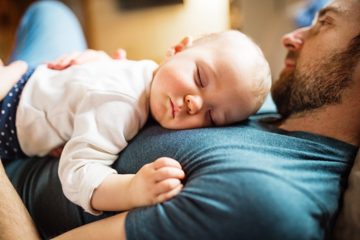Ein Baby schläft auf dem Bauch seines Vaters.