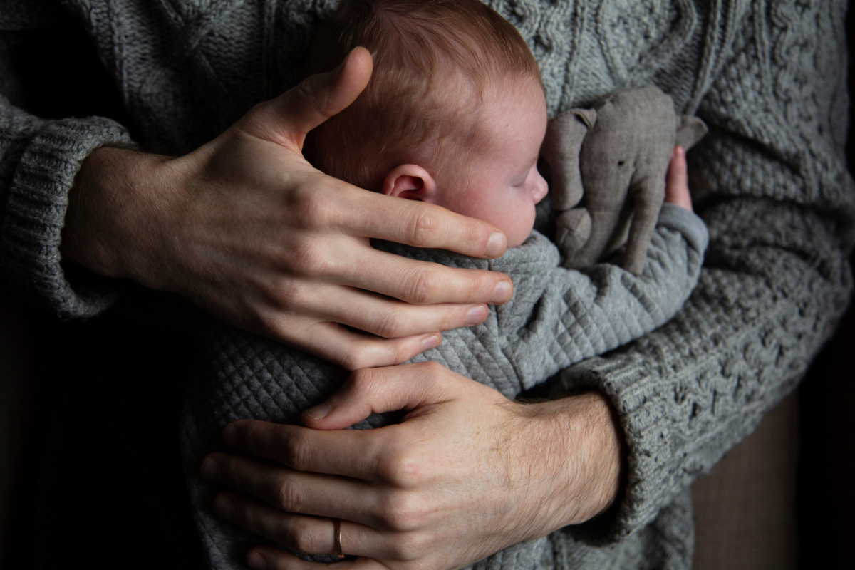 Ein Mann umarmt ein Baby, das ein Kuscheltier festhält.