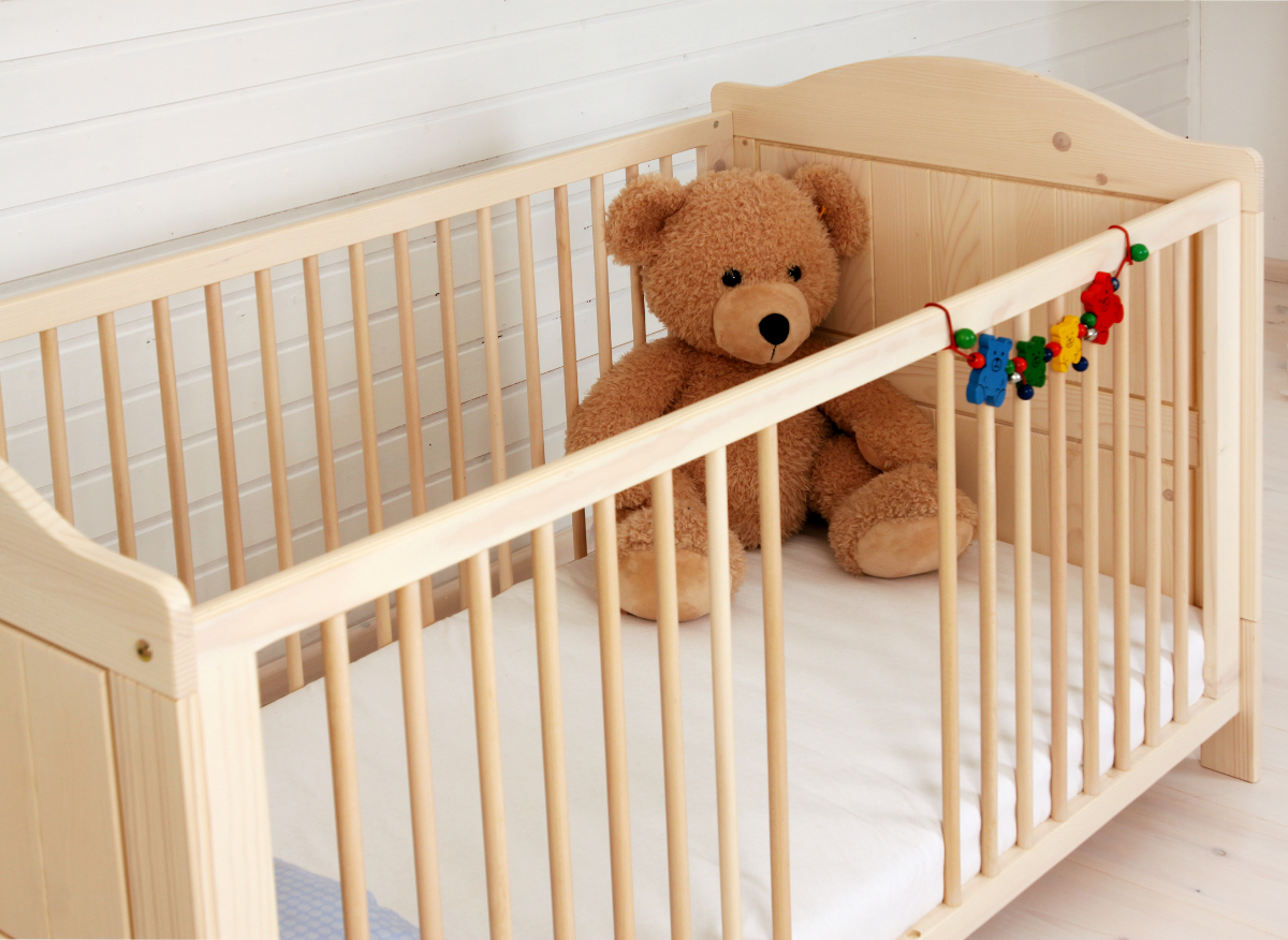 Ein Bild von einem Kinderbett, in dem ein Teddybär liegt.