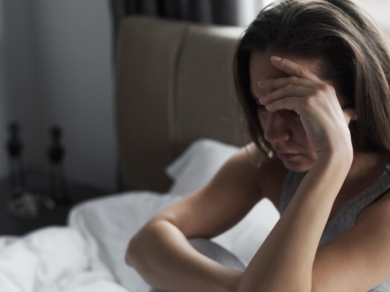 Eine Frau sitzt weinend in ihrem Bett.