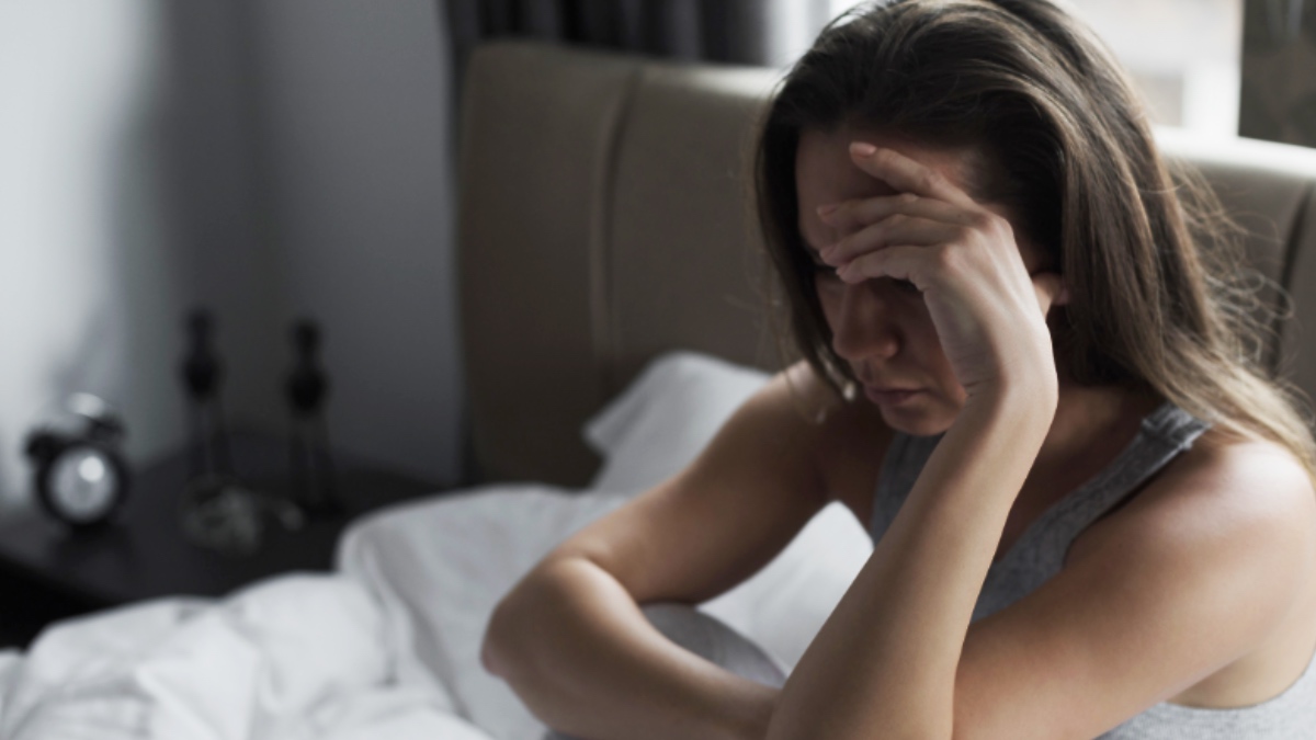 Eine Frau sitzt weinend in ihrem Bett.